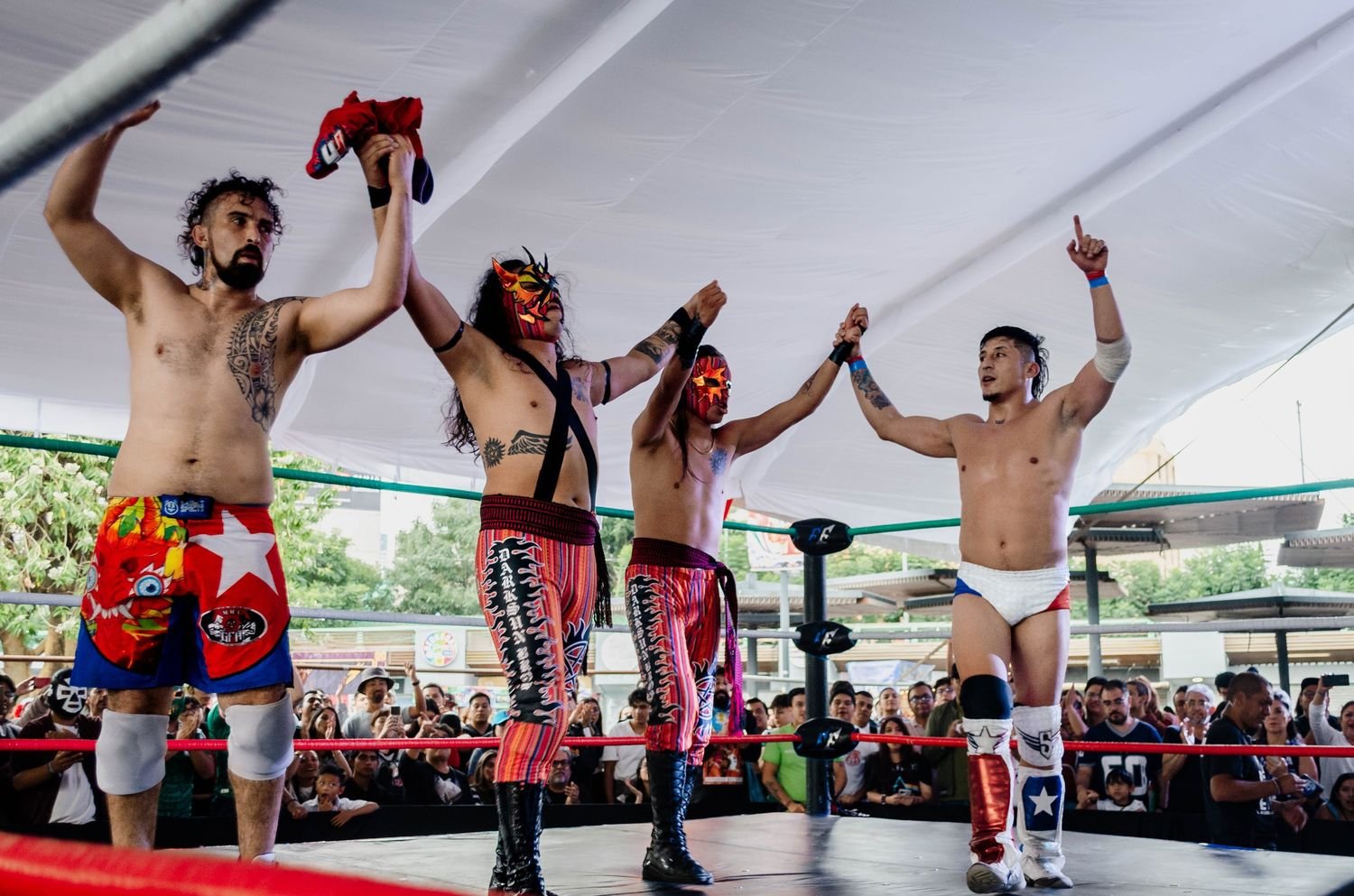 Cuatro luchadores con los brazos en alto al terminar la función