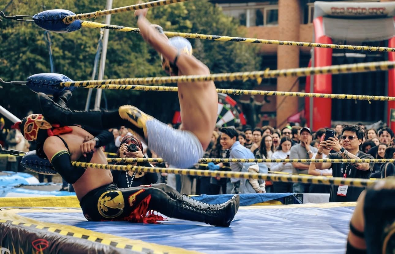 Luchador cayendo sobre las cuerdas mientras el público toma fotos