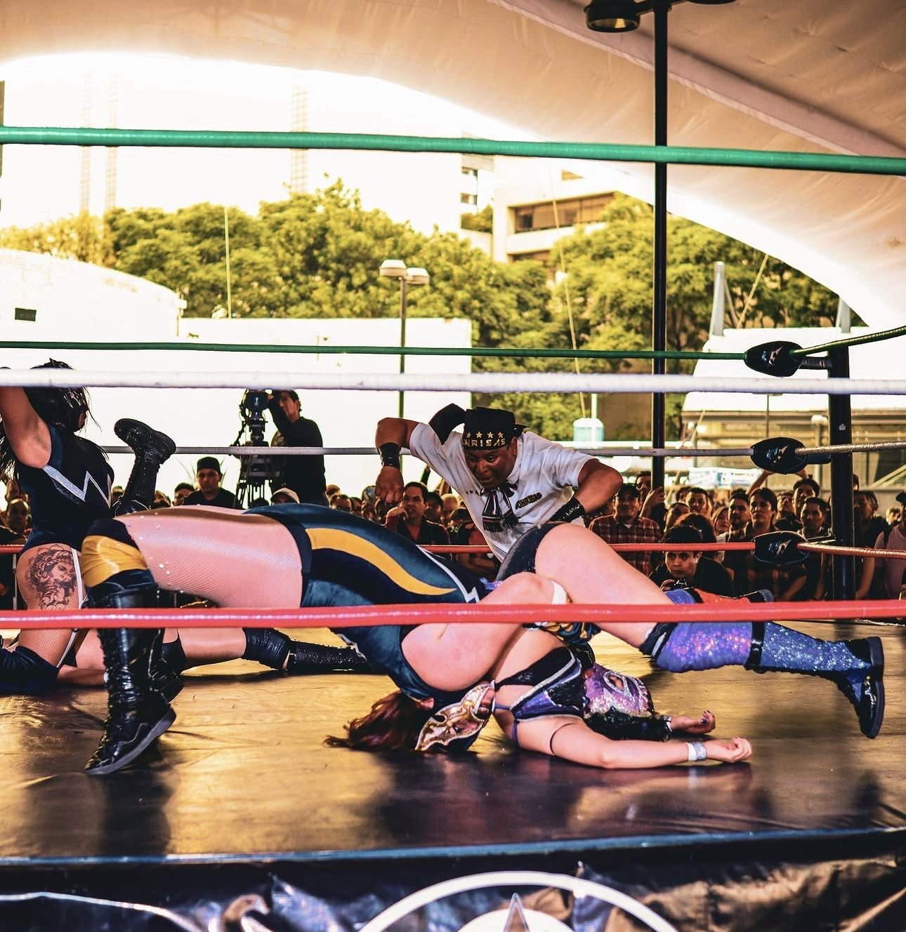 Lucha femenil con un réferi al centro del ring